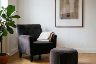 Fauteuil et pouf assortis en velours anthracite dans un salon moderne au parquet en chêne clair