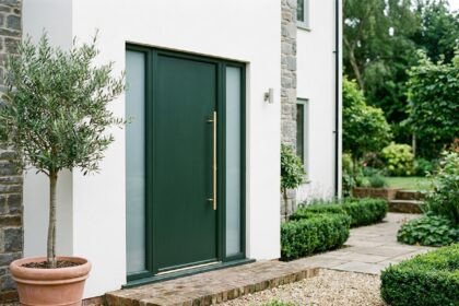 Nouvelle porte d'entrée verte forêt avec poignée en laiton brossé sur façade maison rénovée